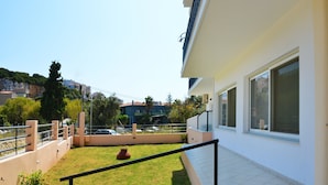 A residential building with a small lawn, a metal railing, and a tiled floor. - Despoina (Skiathos)