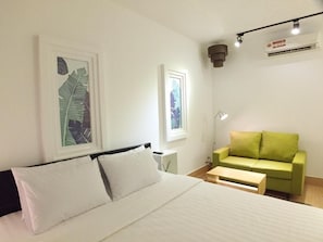 A bedroom with a bed, a green sofa, a desk, and two framed pictures on the wall. - Cozycloud Backpackers Hostel (Siem Reap)