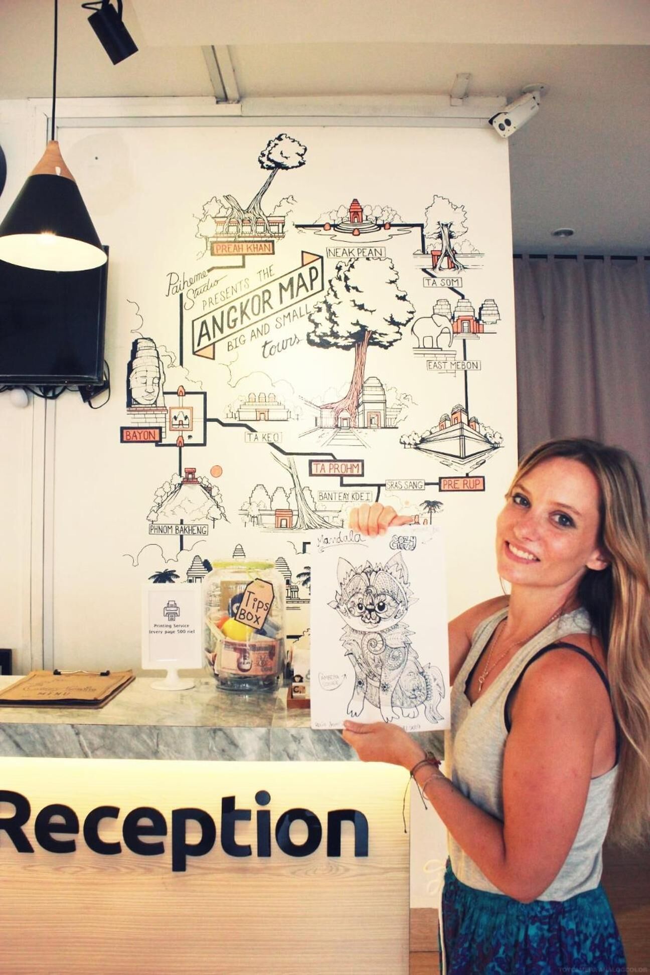 Eine Person hält eine Karte am Empfangstisch, wo ein Schild mit der Aufschrift 'Reception' steht.