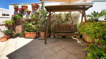 A patio area with a wooden bench, potted plants, and a pergola.