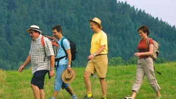 A group of people hiking in a grassy field with a forest in the background.