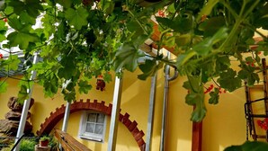 Un bâtiment jaune avec une arche en briques, une petite fenêtre et une balustrade en bois.