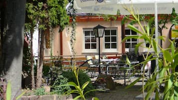 An outdoor seating area with tables and chairs, a stone pathway, and a building with a sign that reads "Valentin's Weisbier."