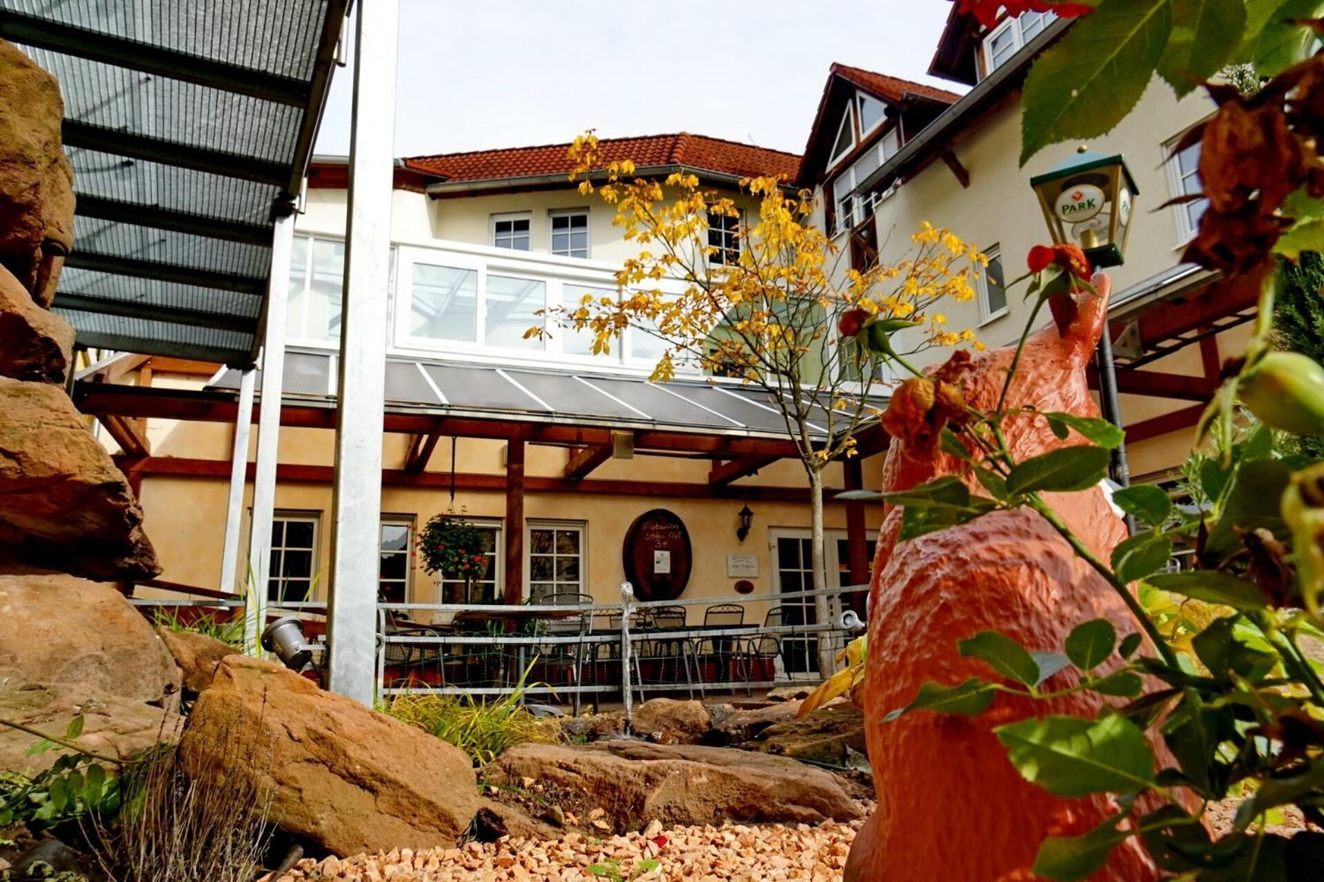 A building with a restaurant sign, outdoor seating, and a rock garden.
