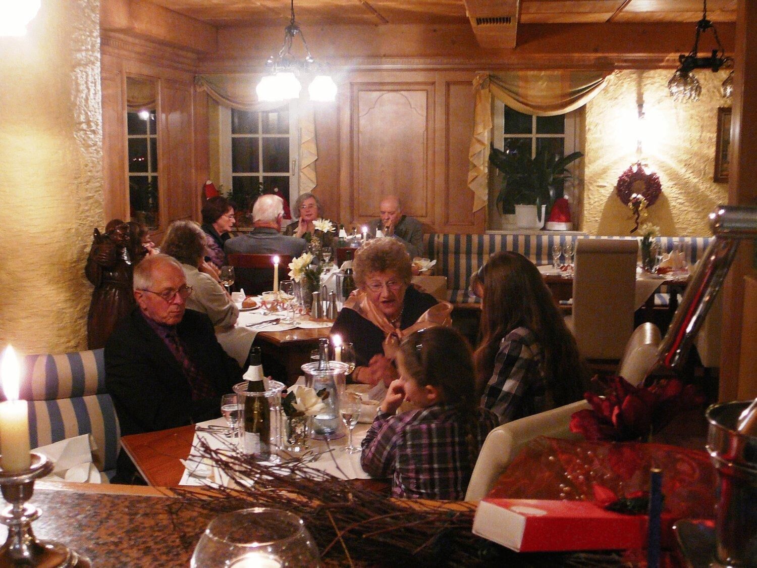 A dining area with wooden paneling, a chandelier, and a table set for a meal.