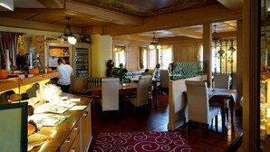 Un restaurant avec un décor intérieur en bois, un espace buffet et un coin salon avec des tables et des chaises.