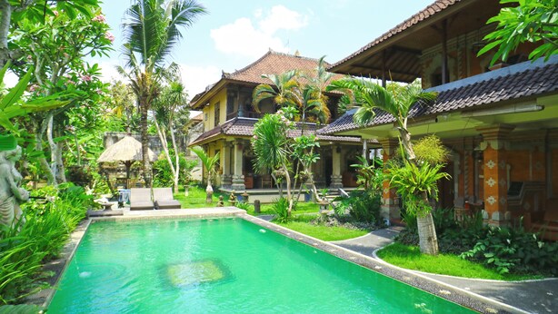 Ein traditionelles Haus mit Swimmingpool, umgeben von üppiger Vegetation.