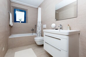 A modern bathroom with a bathtub, toilet, and vanity.