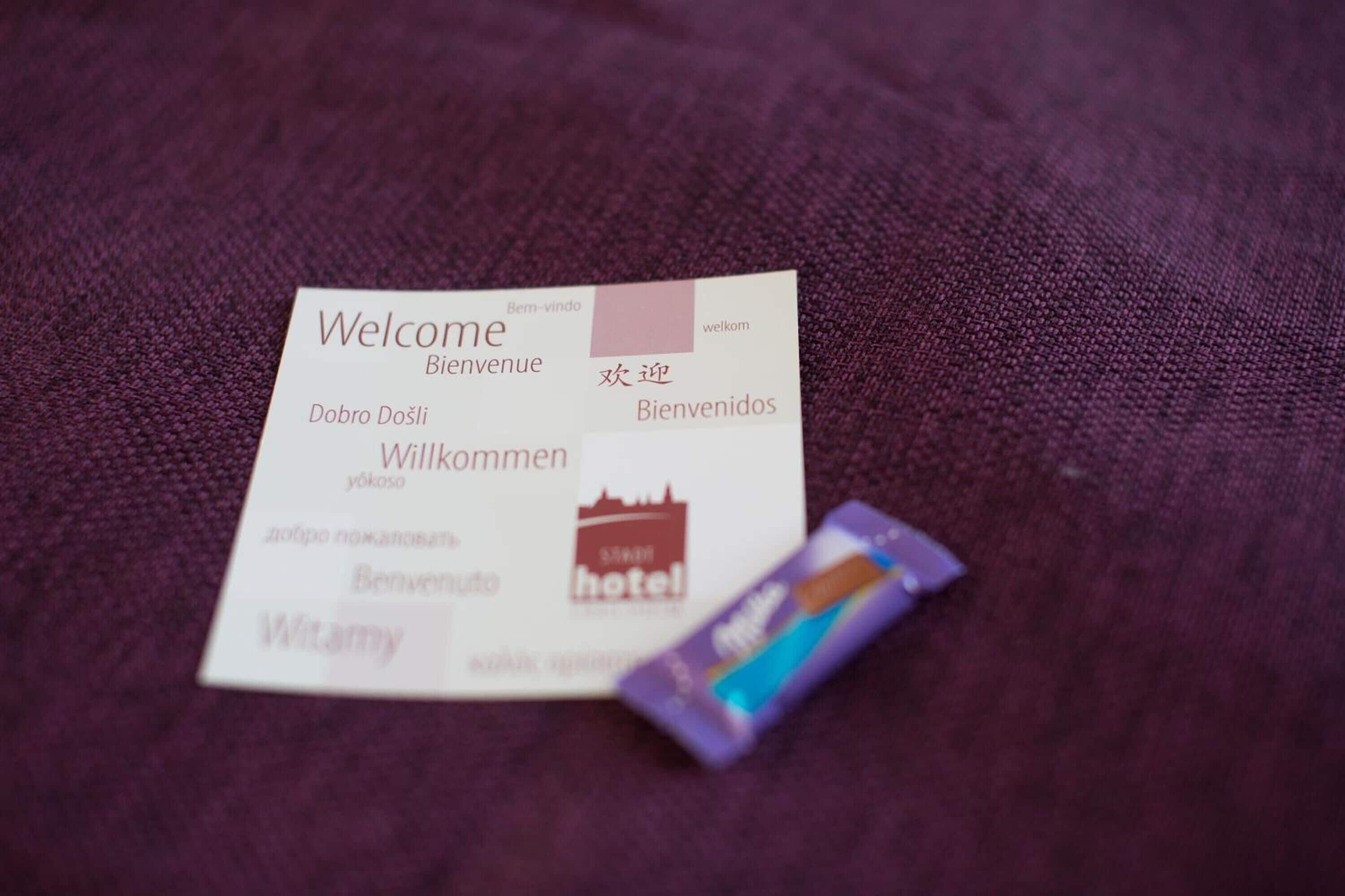 A welcome card with multilingual greetings and a hotel logo.