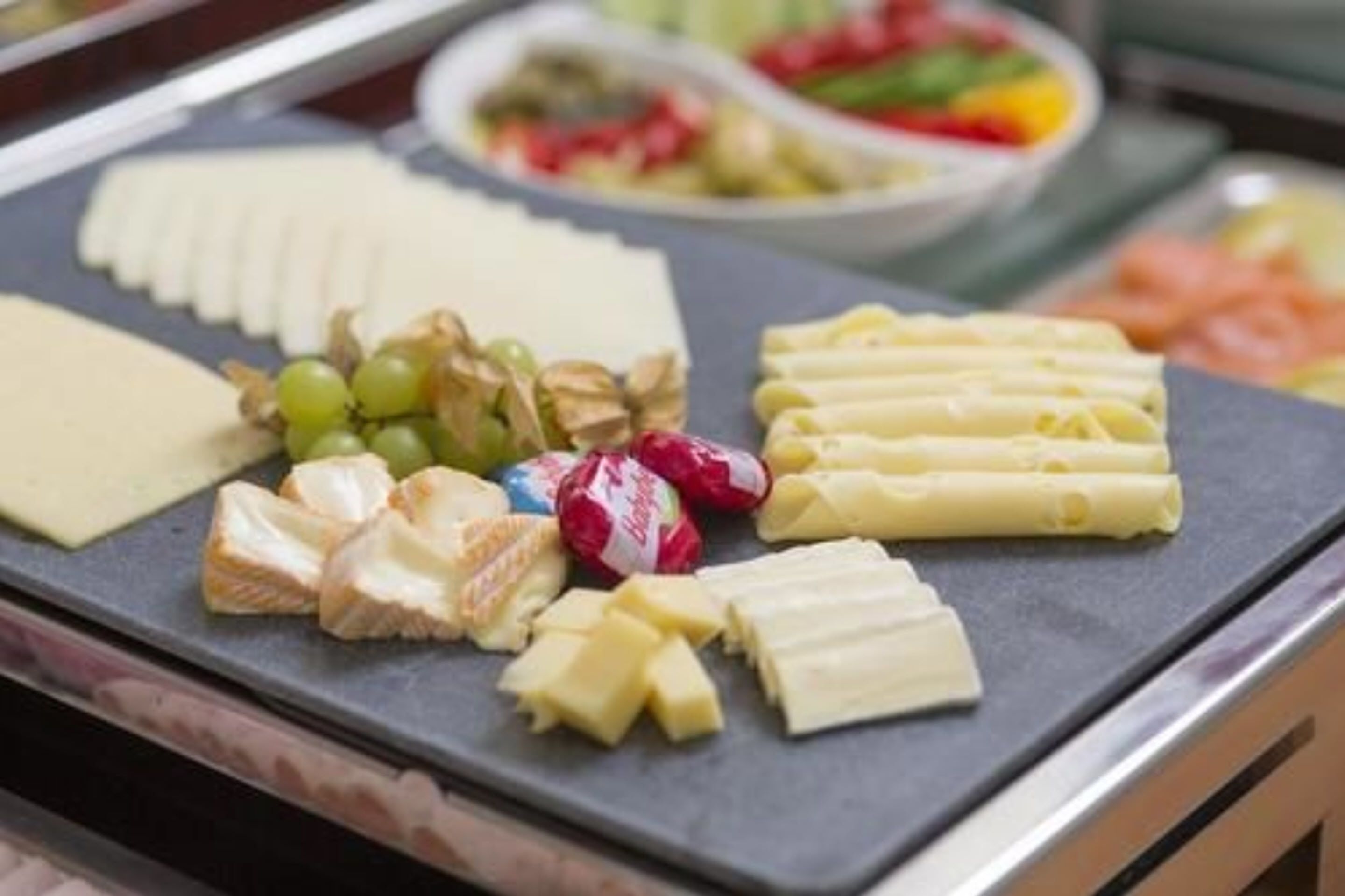 A cheese board with various cheeses, grapes, and nuts.