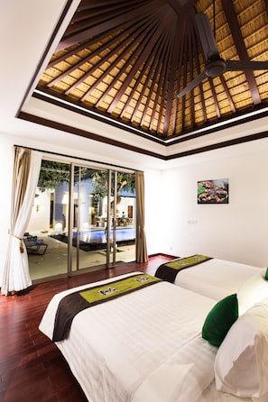 A hotel room with a large bed, a ceiling fan, and a view of a swimming pool through a glass door.