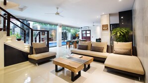 A modern living room with a sofa, coffee table, and a staircase. - Sunset Paradise Villa Jimbaran 3003 (Kedonganan)