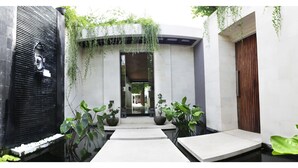 A modern indoor garden with a water feature, potted plants, and a wooden door. - Sunset Paradise Villa Jimbaran 8008 (Kedonganan)