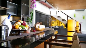 A modern kitchen with a bar area, featuring a fruit display, a bottle of alcohol, and a plant. - Sunset Paradise Villa Jimbaran 8008 (Kedonganan)