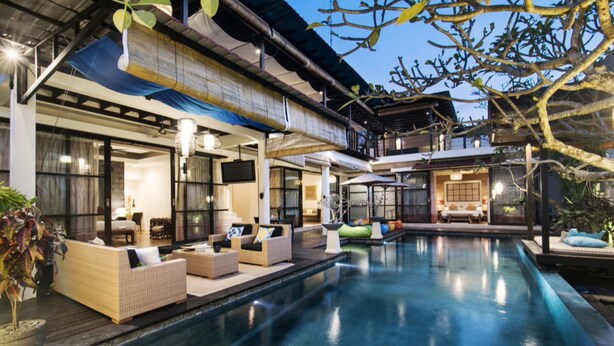 A poolside area with wicker furniture, a flat-screen TV, and a covered seating area. - Sunset Paradise Villa Temple Hill (Jimbaran)