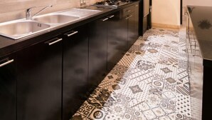 A modern kitchen with dark cabinetry, a stainless steel sink, and a patterned floor. - Sunset Paradise Villa Temple Hill (Jimbaran)
