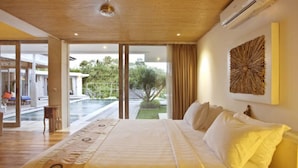 A spacious bedroom with a large bed, a view of a swimming pool, and a ceiling fan. - Sunset Paradise Villa Uluwatu (Pecatu)