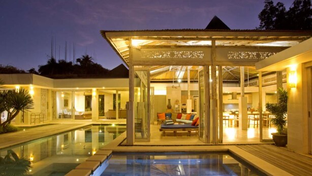 A modern resort with a glass-enclosed lounge area, a swimming pool, and a dining area. - Sunset Paradise Villa Uluwatu (Pecatu)