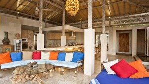 A spacious living area with a high ceiling, a round glass coffee table, and a sofa with colorful cushions. - Sunset Paradise Villa Uluwatu (Pecatu)