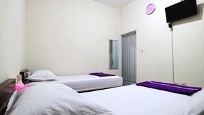 A hotel room with two beds, a TV mounted on the wall, a clock, and a door. - Casa Sidoluhur 17 (Surabaya)