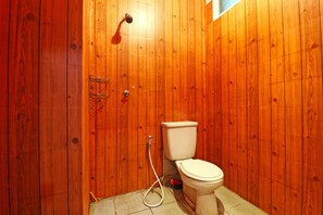 Bathroom features a toilet and shower area with a hose.