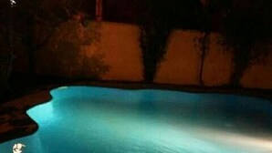 Una piscina por la noche con una fuente de luz en el borde del agua.
