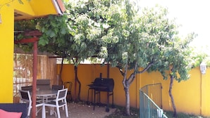Un patio exterior con una mesa, sillas, una parrilla y una piscina.
