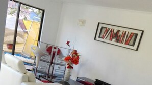 Una sala de estar con dos sofás blancos, un tapete rojo y un cuadro en la pared.
