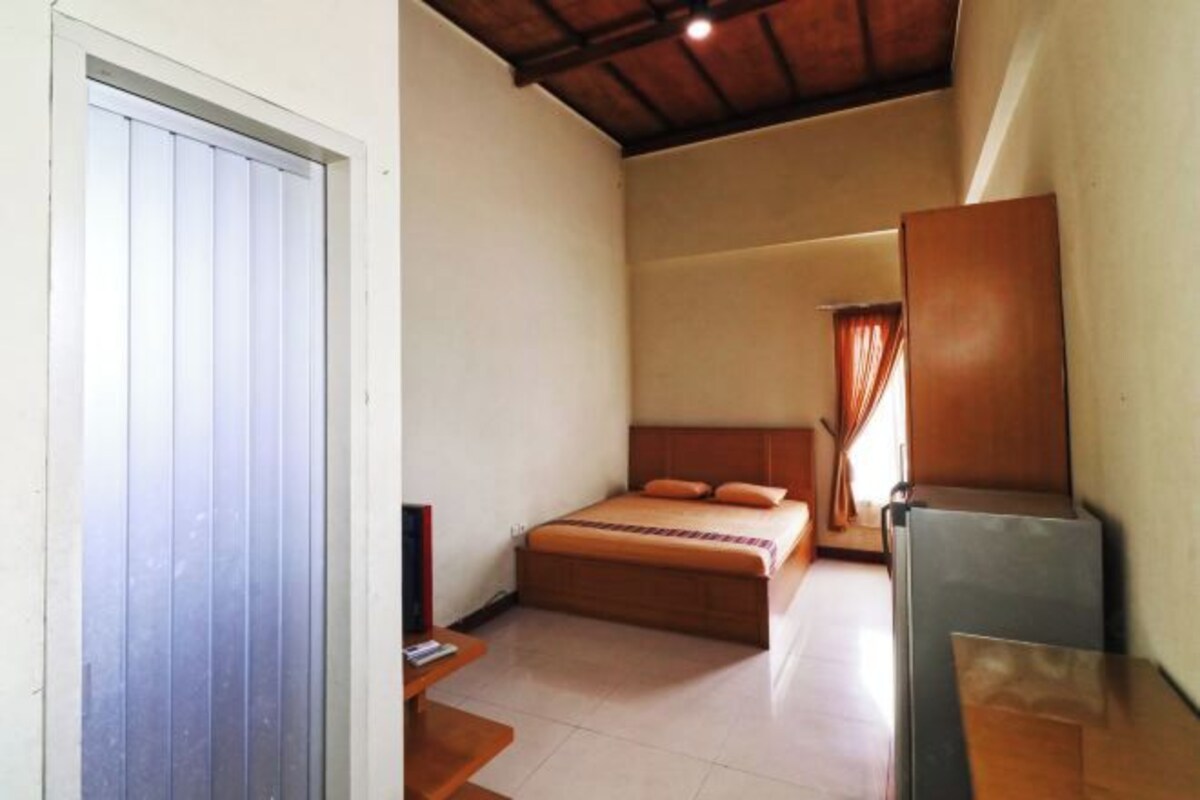 A bedroom with a bed, a desk, and a wardrobe.