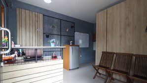 A modern kitchen with wooden cabinets, a refrigerator, and a bar area with stools. - Bedur Homestay Syariah (Bekasi)