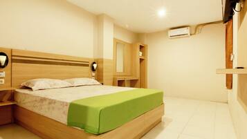 A bedroom with a wooden bed, a nightstand, a green bedspread, a wall-mounted air conditioner, and a wooden wardrobe.