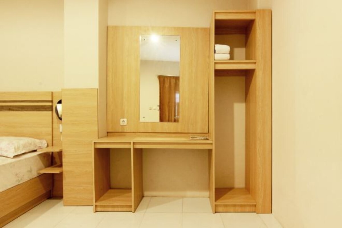 A compact bedroom with a bunk bed, a desk with a mirror, and a wardrobe.
