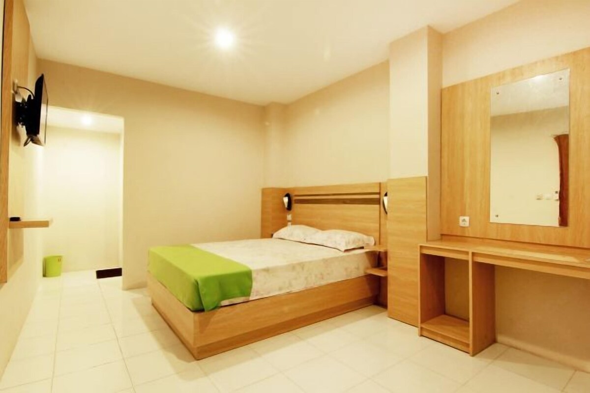 A bedroom with a wooden bed, a bedside table, a mirror, and a small shelf.