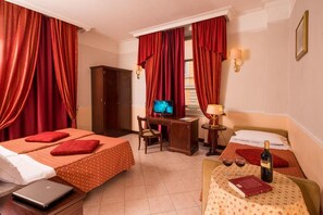 A hotel room with two beds, a desk, a television, a laptop, a bottle of wine, and a book. - Hotel Nizza (Roma)