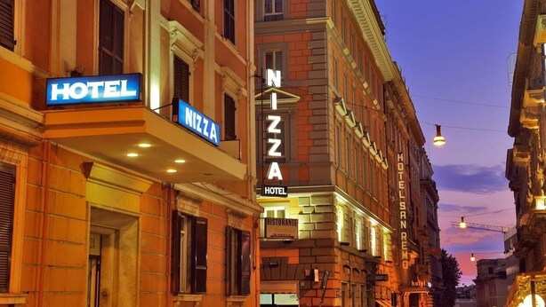 Un hôtel avec une enseigne indiquant « HÔTEL » et une autre indiquant « PIZZA ».