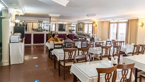 A spacious dining area with multiple tables and chairs, a kitchen in the background, and a modern interior design. - Grand Lara Hotel (Istanbul)