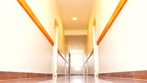 A long, narrow hallway with a polished floor and wooden handrails on both sides. - Mapletree Inn (Bengaluru)
