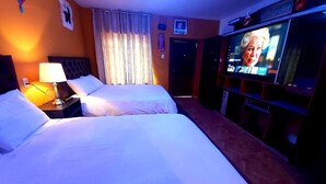 Habitación de hotel con dos camas, un televisor y una mesita de noche.