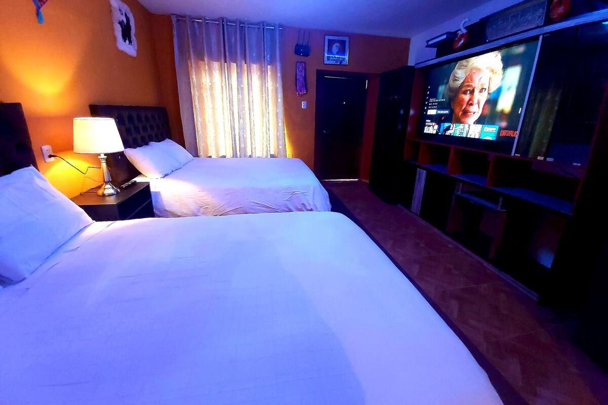 A hotel room with two beds, a TV, and a nightstand.