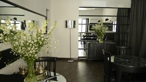 A modern dining area with a round glass table, black chairs, and a vase with flowers. - Hotel Opera (Tbilisi)