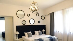 A modern bedroom with a large bed, bedside tables, a geometric chandelier, and multiple wall-mounted mirrors. - Hotel Opera (Tbilisi)