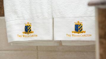 Dos toallas blancas con logotipos bordados y texto que dice "The Wells Carlton".