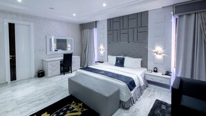 Un dormitorio moderno con una cama grande, mesitas de noche, un tocador y una televisión.