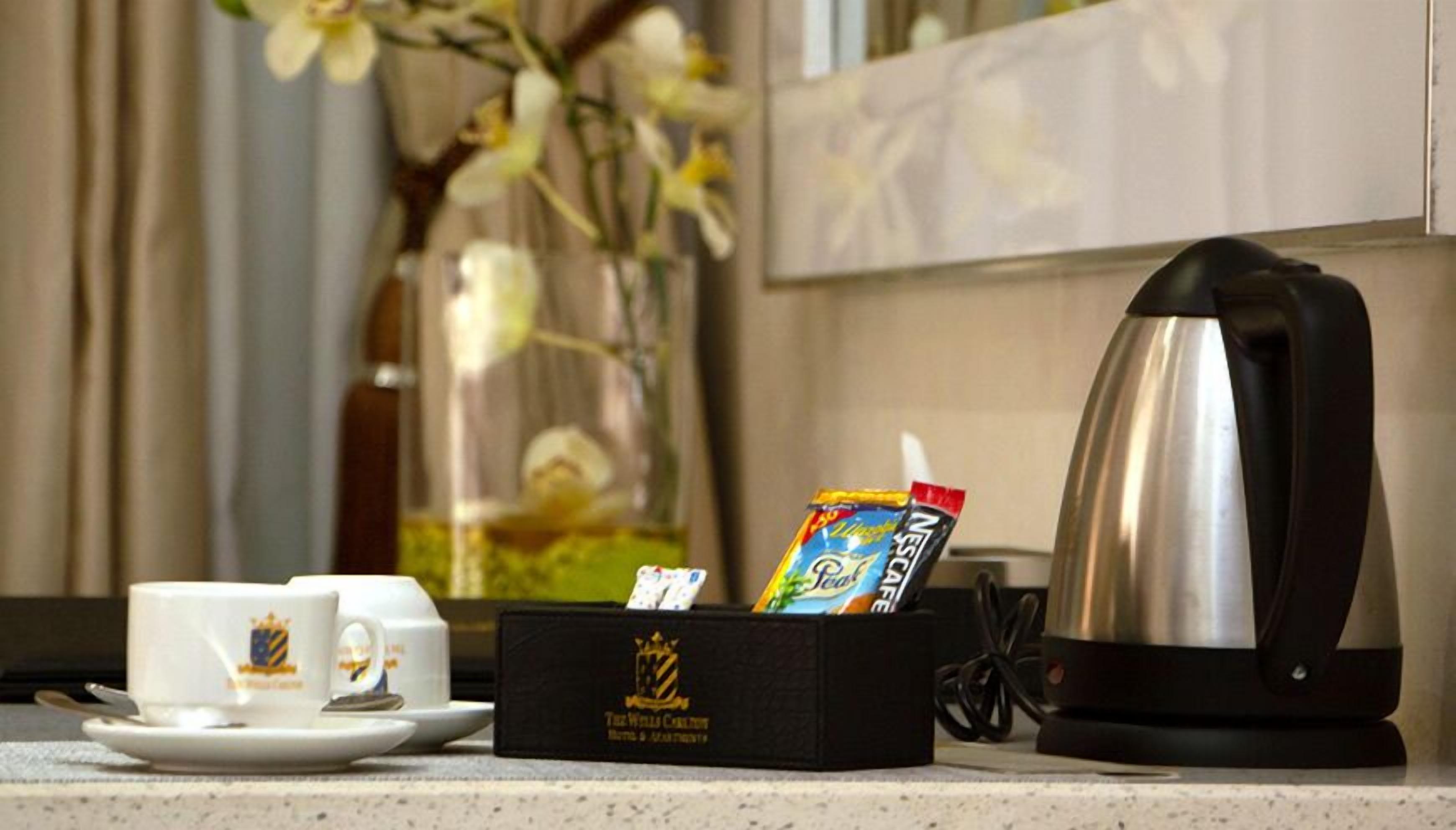 Una cafetera, una caja de cápsulas de café y una taza de café sobre una encimera.
