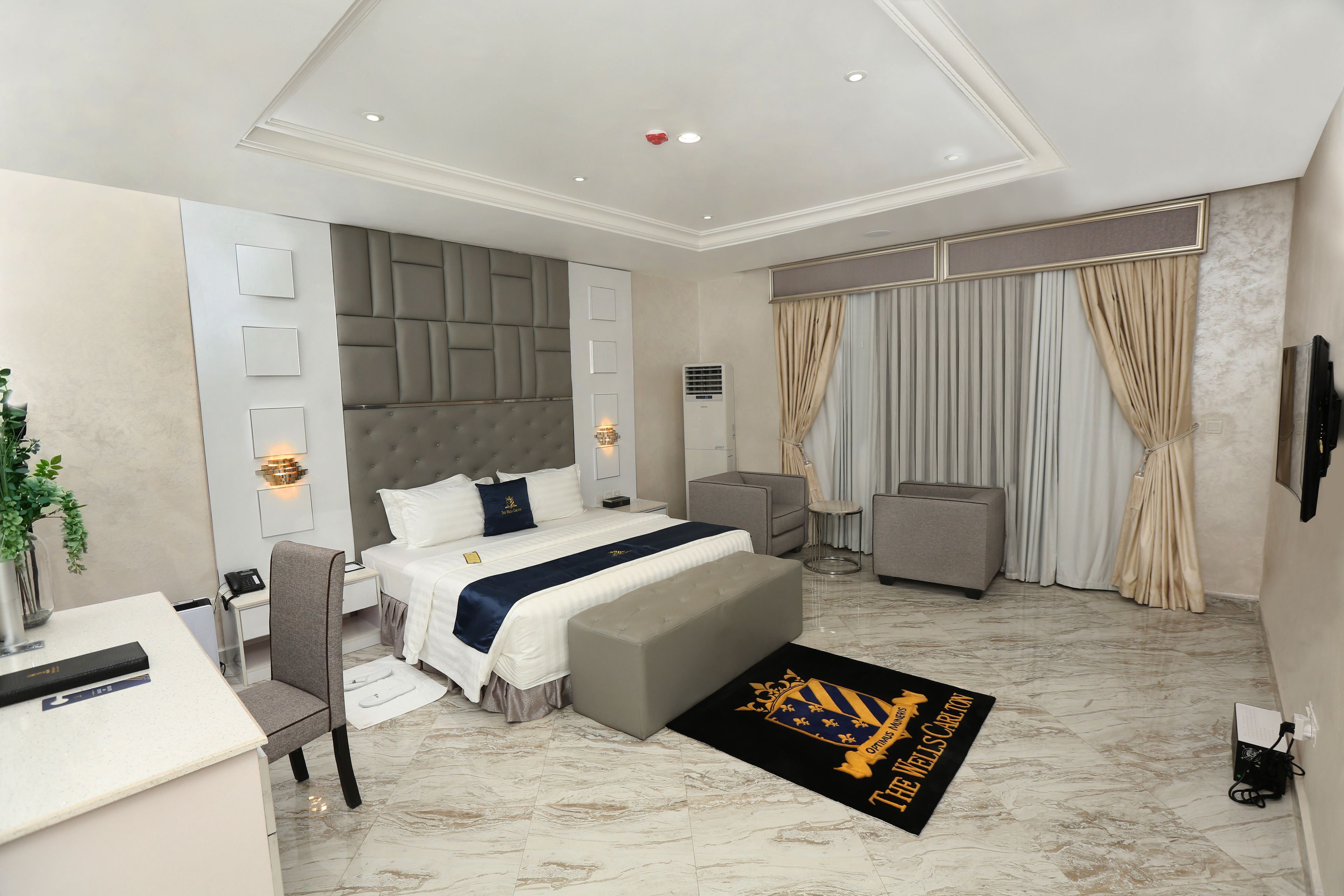Une chambre d’hôtel moderne équipée d’un grand lit, d’un bureau, d’une chaise, d’un canapé et d’une télévision.