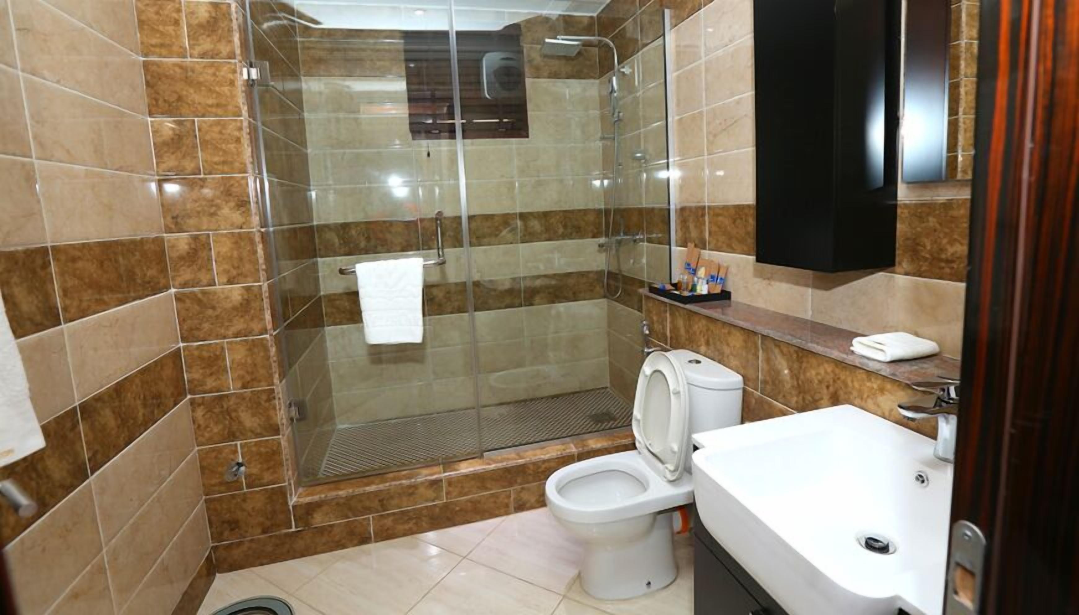 A bathroom with a glass-enclosed shower, a toilet, and a sink.