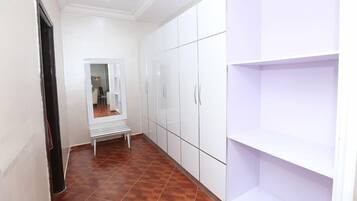 A hallway with a bench, white cabinets, and a tiled floor.