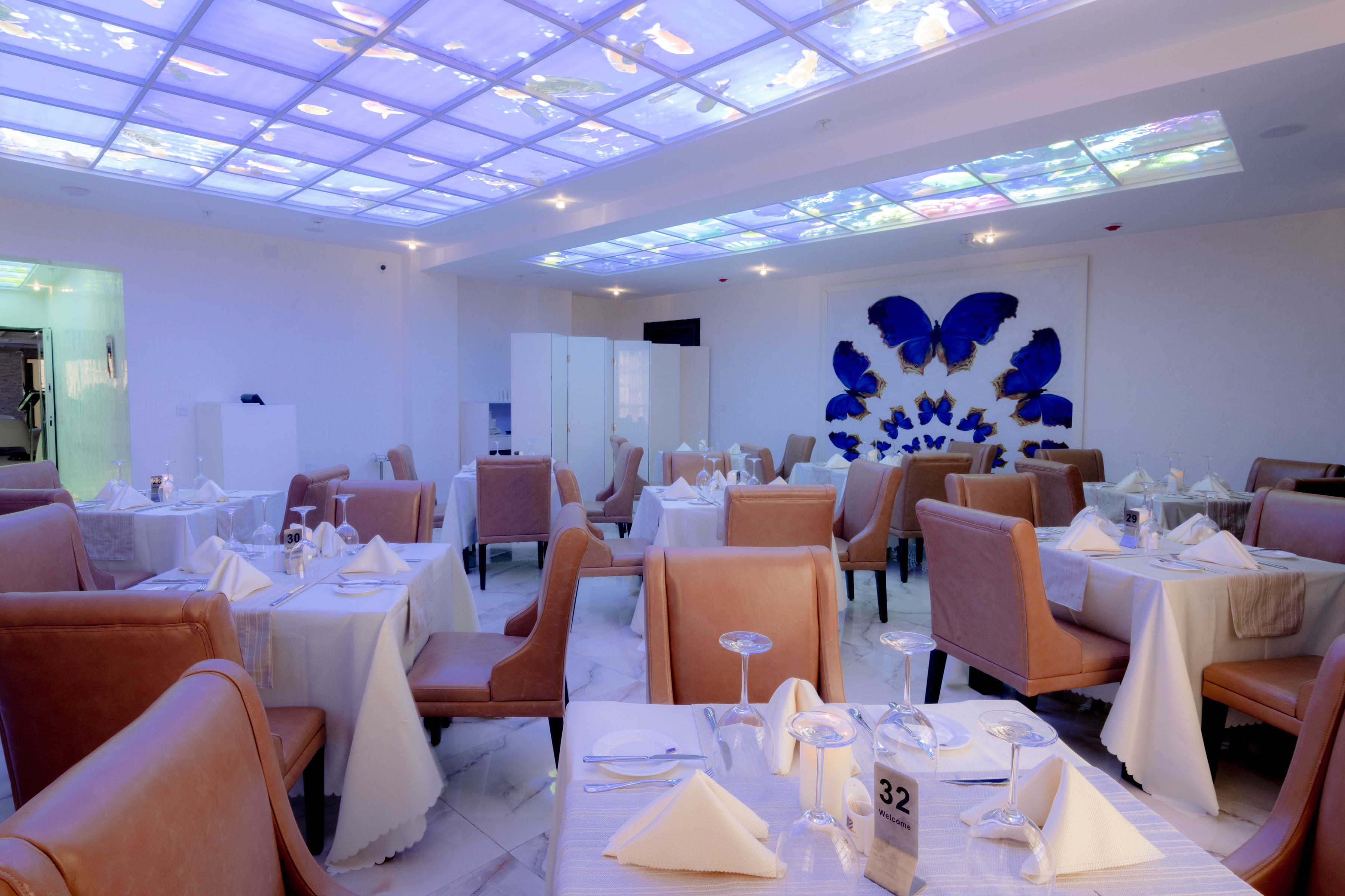 Ein Restaurant mit gedeckten Tischen, einer Fischdecke und einer Wand mit einem Schmetterlingsdesign.