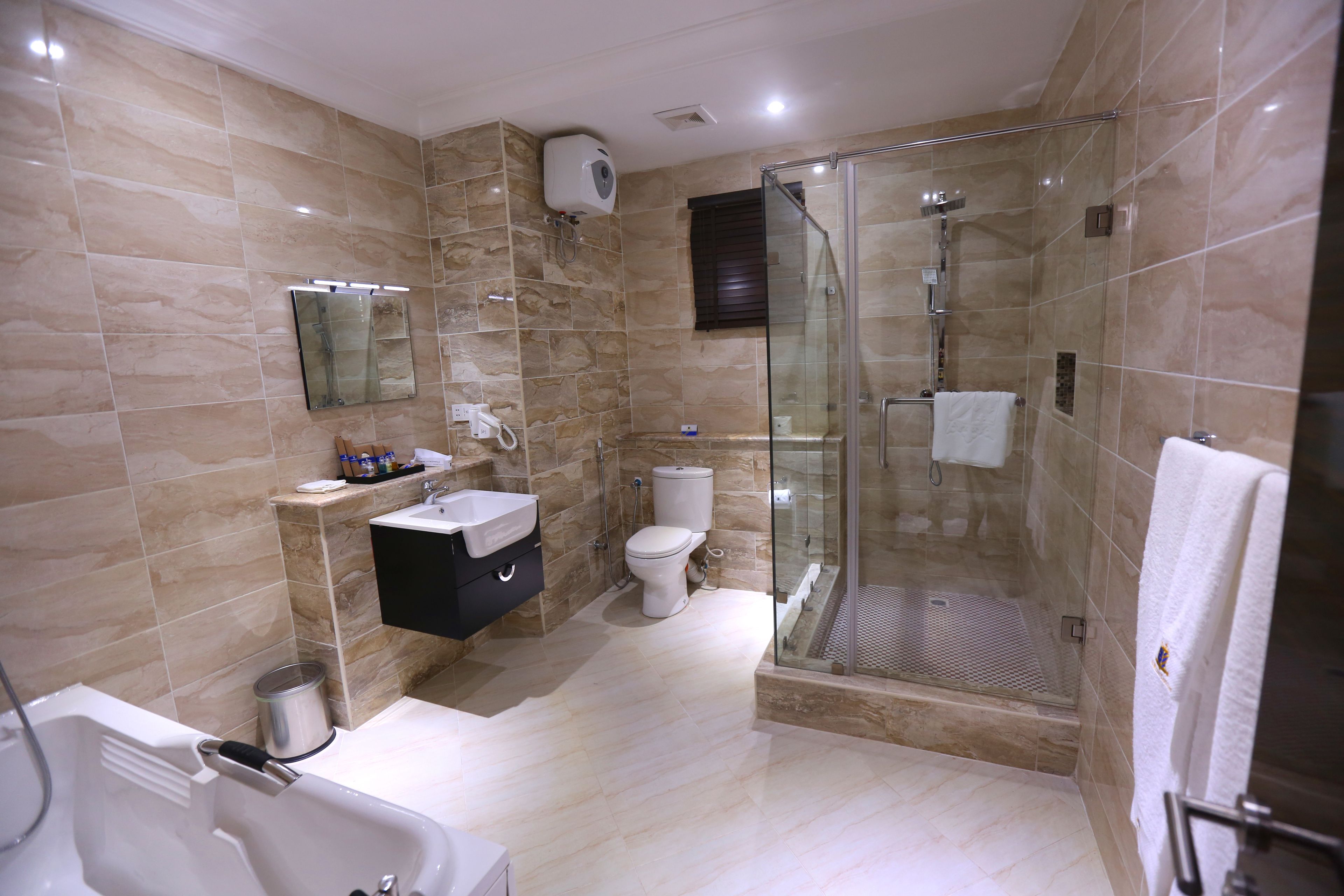 A modern bathroom with a glass-enclosed shower, a white bathtub, and a vanity with a mirror.
