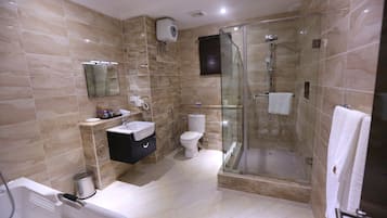 A modern bathroom with a glass-enclosed shower, a white bathtub, and a vanity with a mirror.